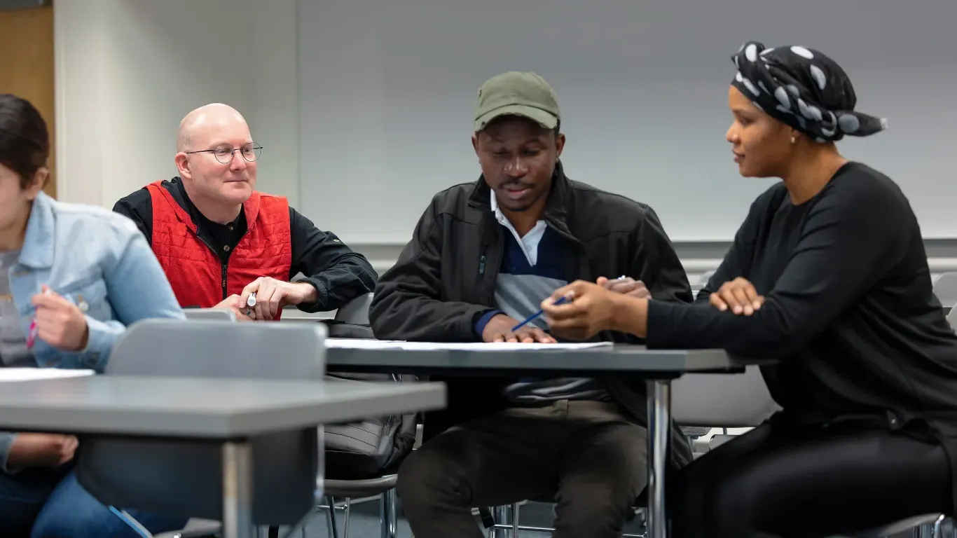 two students talking with an instructor listening