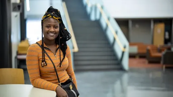 student smiling by stairs and windows