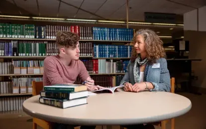 student sitting at a table talking with an advisor 