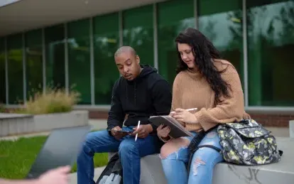 two students sitting outside talking