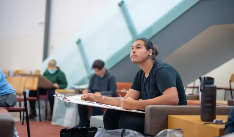 Students will large drawing boards drawing in a lounge 